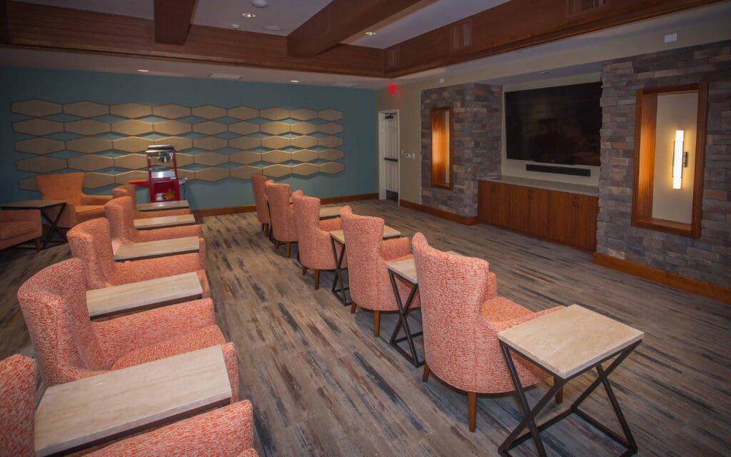 Sage Desert Tucson AZ 2018 June -0222 - The Ranch Estates of Tucson A movie theater room with rows of pink sofa chairs facing the TV, and a popcorn machine against the wall.