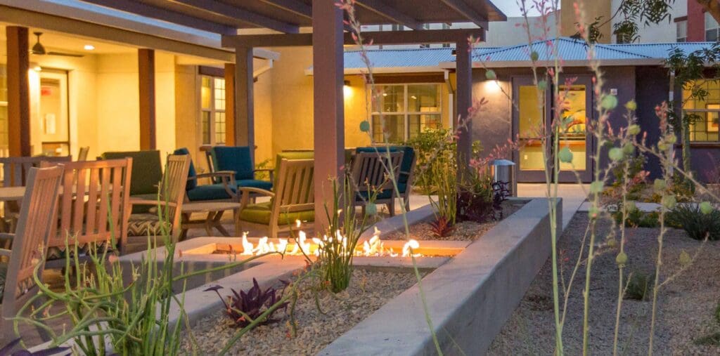 The Ranch Estates of Tucson outdoor courtyard with a fireplace, tables, and chairs.
